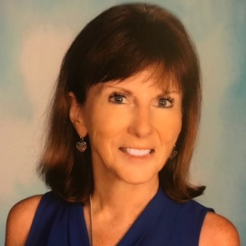 headshot of Sue Heraper in blue shirt with grey background